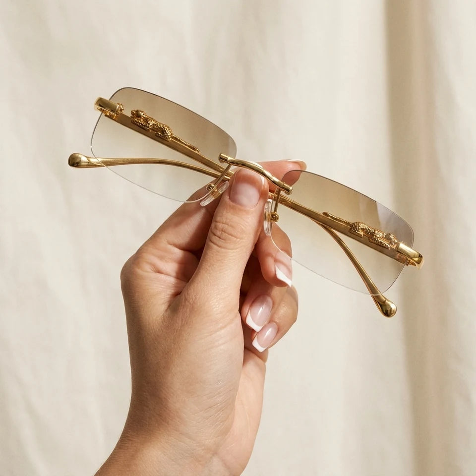 Gafas Jaguar sostenidas en mano contra fondo neutro