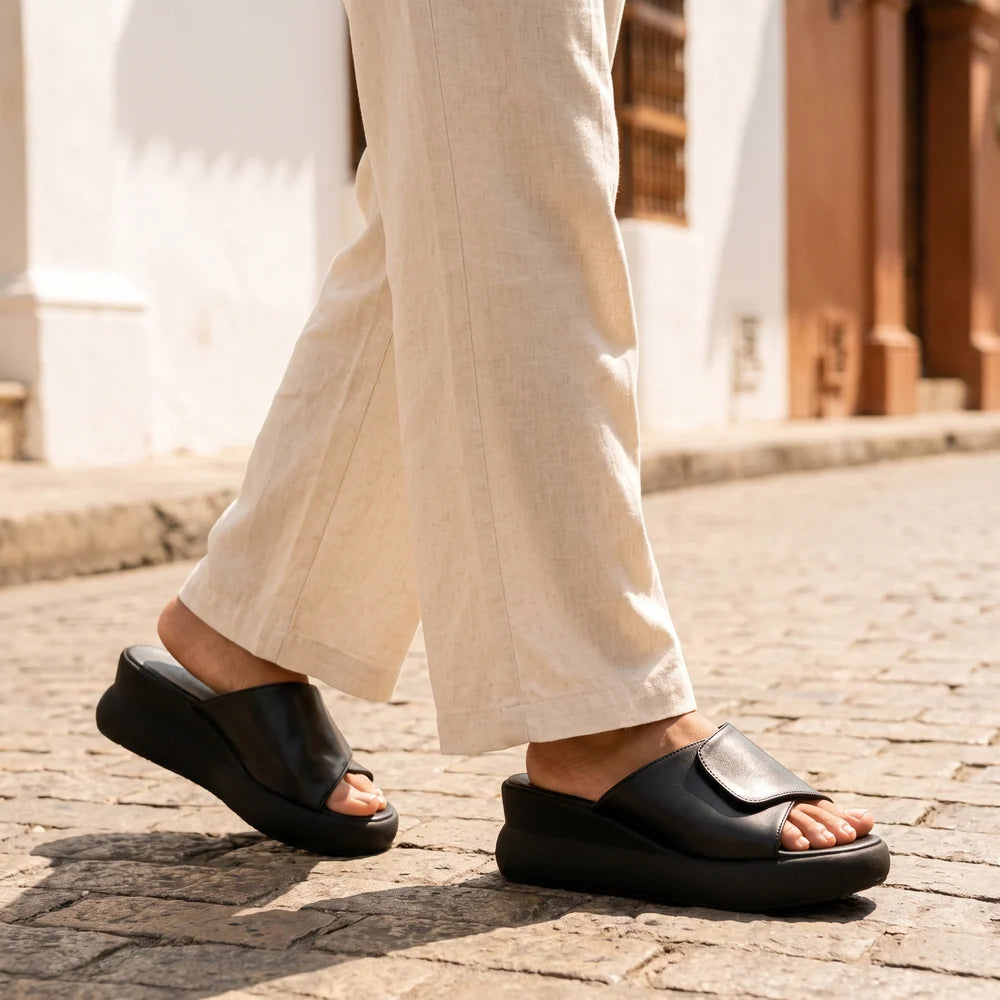 Mujer caminando por una calle empedrada con sandalias de plataforma negras